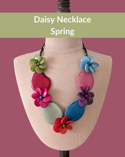 Colorful necklace with floral designs on a mannequin bust against a pink background