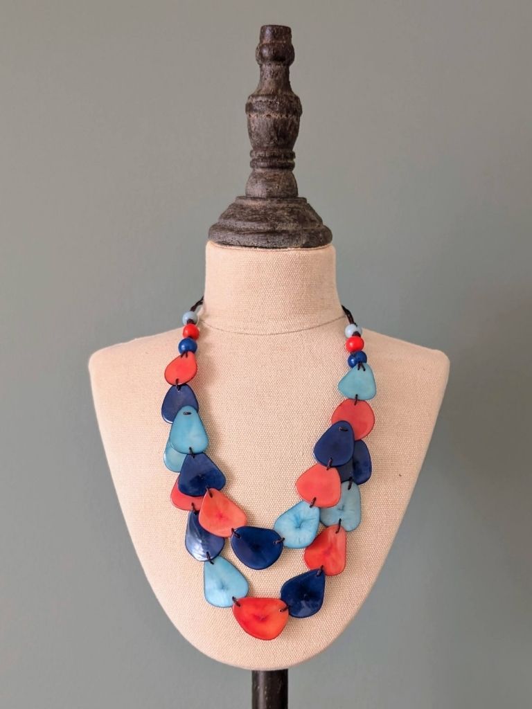 Necklace with red, blue, and orange heart-shaped beads on a mannequin bust against a gray background