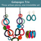 Three coulorful artisan jewelry pieces displayed on a white background with a teal banner at the top reading 'Galapagos Trio' and 'Three artisan pieces, one irresistible set.' The set includes a long tagua necklace, matching earrings, and a tagua bracelet.