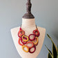 Colorful necklace on a mannequin bust with a plant in the background