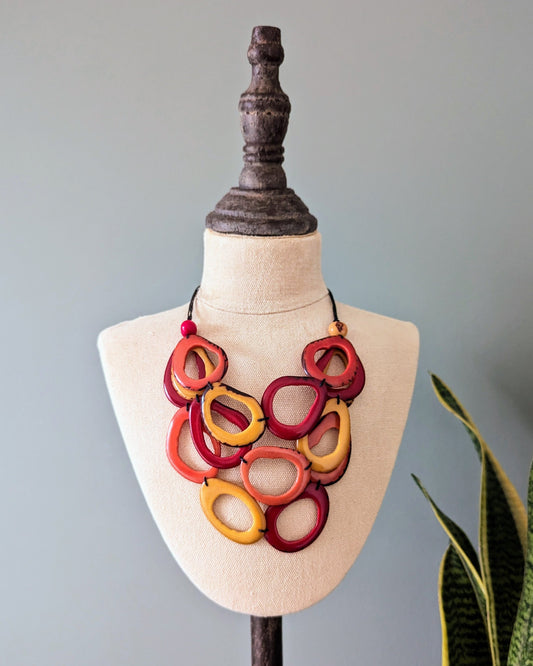 Colorful necklace on a mannequin bust with a plant in the background