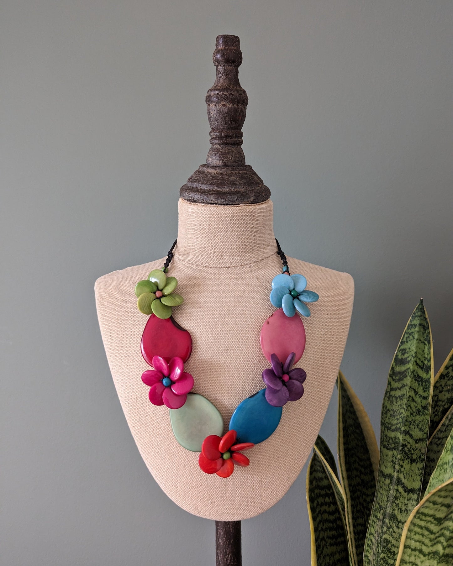 Colorful floral necklace on a mannequin bust with a gray background
