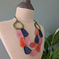 Colorful necklace on a mannequin bust with a plant in the background