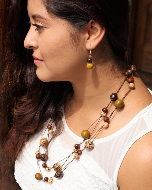 a woman wearing a long necklace that it is made of cream and brown acai seeds and brown,cream and olive pambil seeds